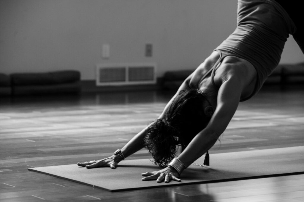 Black and white image of woman in downward facing dog pose.