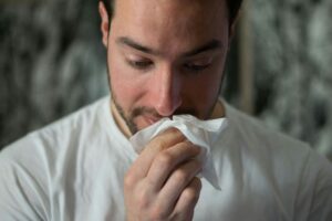 "Person sneezing into a tissue depicting seasonal allergies.